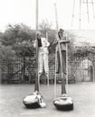 Man and woman on stilts holding giant golf clubs