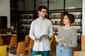 Man and woman students holding books and talking while standing in library Royalty Free Stock Photo