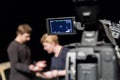 A man and a woman in the Studio preparing to shoot. Video camera with LCD display in the foreground Royalty Free Stock Photo