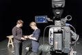 A man and a woman in the Studio preparing to shoot. Video camera with LCD display in the foreground Royalty Free Stock Photo