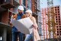 Man and woman studying building plan at construction site. Royalty Free Stock Photo