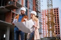 Man and woman studying building plan at construction site. Royalty Free Stock Photo