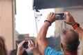 A man and a woman take photos of the performance of the open-air rock band The Queen Kings on their mobile phone cameras.