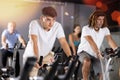 Man and woman taking indoor cycling class at fitness center, doing cardio riding bike Royalty Free Stock Photo