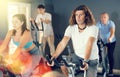 Man and woman taking indoor cycling class at fitness center, doing cardio riding bike Royalty Free Stock Photo