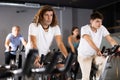 Man and woman taking indoor cycling class at fitness center, doing cardio riding bike Royalty Free Stock Photo