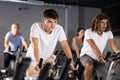 Man and woman taking indoor cycling class at fitness center, doing cardio riding bike Royalty Free Stock Photo
