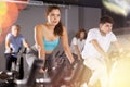 Man and woman taking indoor cycling class at fitness center, doing cardio riding bike Royalty Free Stock Photo