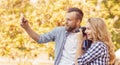 Man and woman taking photos with a camera and a smartphone in autumn park.