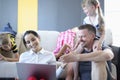 Man and woman and their children are smiling and laughing while sitting on floor and looking at laptop.