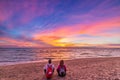 Man and woman together relaxing on sand beach romantic sky at sunset. Real people getting away from it all. Dramatic clouds over Royalty Free Stock Photo