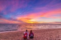 Man and woman together relaxing on sand beach romantic sky at sunset. Real people getting away from it all. Dramatic clouds over Royalty Free Stock Photo