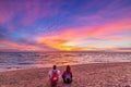 Man and woman together relaxing on sand beach romantic sky at sunset. Real people getting away from it all. Dramatic clouds over Royalty Free Stock Photo