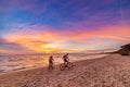 Man and woman together riding bicycle on sand beach romantic sky at sunset. Real people getting away from it all. Dramatic clouds Royalty Free Stock Photo