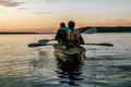 A man and woman tourists floating in a canoe at sunset on lake L