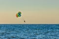 Man and woman tourists are flying on parasailing over the sea against the backdrop of the sunset sky and the horizon. Extreme Royalty Free Stock Photo