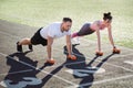 Man and a woman train with dumbbells at the stadium in the summer. Sports lifestyle. Royalty Free Stock Photo