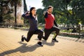 Man and woman training with weights in a city square