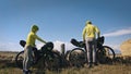 The man and woman travel on mixed terrain cycle touring with bikepacking. The two people journey with bicycle bags