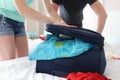Man and woman trying to close suitcase with clothes closeup Royalty Free Stock Photo