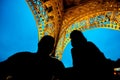Man with and woman under the Eiffel Towet at night, people silhouettes