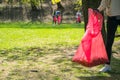 Man and woman volunteer wearing picking up trash and plastic waste in public park. Young people wearing gloves and putting litter