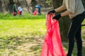 Man and woman volunteer wearing picking up trash and plastic waste in public park. Young people wearing gloves and putting litter