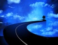 A man and woman walk on a road the goes through clouds leading into the sky or heaven Royalty Free Stock Photo