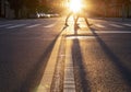 Man and woman walking across the street in New York City with the light of sunset casting long shadows in the intersection Royalty Free Stock Photo