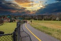 A man and a woman walking a dog along a winding footpath with a yellow line in the park surrounded by green grass Royalty Free Stock Photo