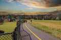 A man and a woman walking a dog along a winding footpath with a yellow line in the park surrounded by green grass Royalty Free Stock Photo