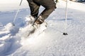 Two people running downhill through deep snow with snoeshoes and hiking sticks.