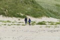 A man and a woman walking in the dunes along Royalty Free Stock Photo