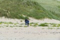 A man and a woman walking in the dunes along Royalty Free Stock Photo