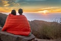 Man and woman watch sunset in blanket Royalty Free Stock Photo