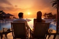 a man and a woman watching the sun rise over sea at a resort, Royalty Free Stock Photo