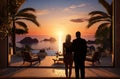 a man and a woman watching the sun rise over sea at a resort, Royalty Free Stock Photo