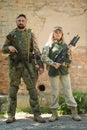 Man and woman with weapons near the destroyed building