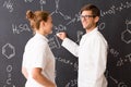 Man and woman wearing labcoats standing in front of a blackboard Royalty Free Stock Photo