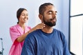 Man and woman wearing physiotherapist uniform having rehab session massaging neck at physiotherpy clinic Royalty Free Stock Photo