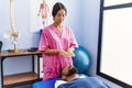 Man and woman wearing physiotherapist uniform having reiki session at physiotherpy clinic Royalty Free Stock Photo