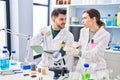 Man and woman wearing scientist uniform writing on notebook at laboratory Royalty Free Stock Photo