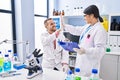 Man and woman wearing scientists uniform high five with hands raised up at laboratory Royalty Free Stock Photo