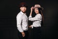 A man and a woman in white shirts and hats on a black background.A couple in love poses in the interior of the studio Royalty Free Stock Photo
