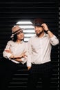A man and a woman in white shirts and hats on a black background.A couple in love poses in the interior of the studio Royalty Free Stock Photo