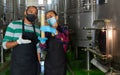 Two winemakers checking winemaking process at factory