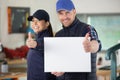 man and woman in workshop holding blank sign with thumbs-up Royalty Free Stock Photo