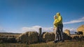 Man and woman in yellow green sportswear. Lovely couple of travelers hug and kiss near old stone enjoying highland