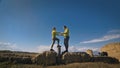 Man and woman in yellow green sportswear. Lovely couple of travelers hug and kiss near old stone enjoying highland Royalty Free Stock Photo