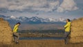 Man and woman in yellow green sportswear. Lovely couple of travelers hug and kiss near old stone enjoying highland Royalty Free Stock Photo